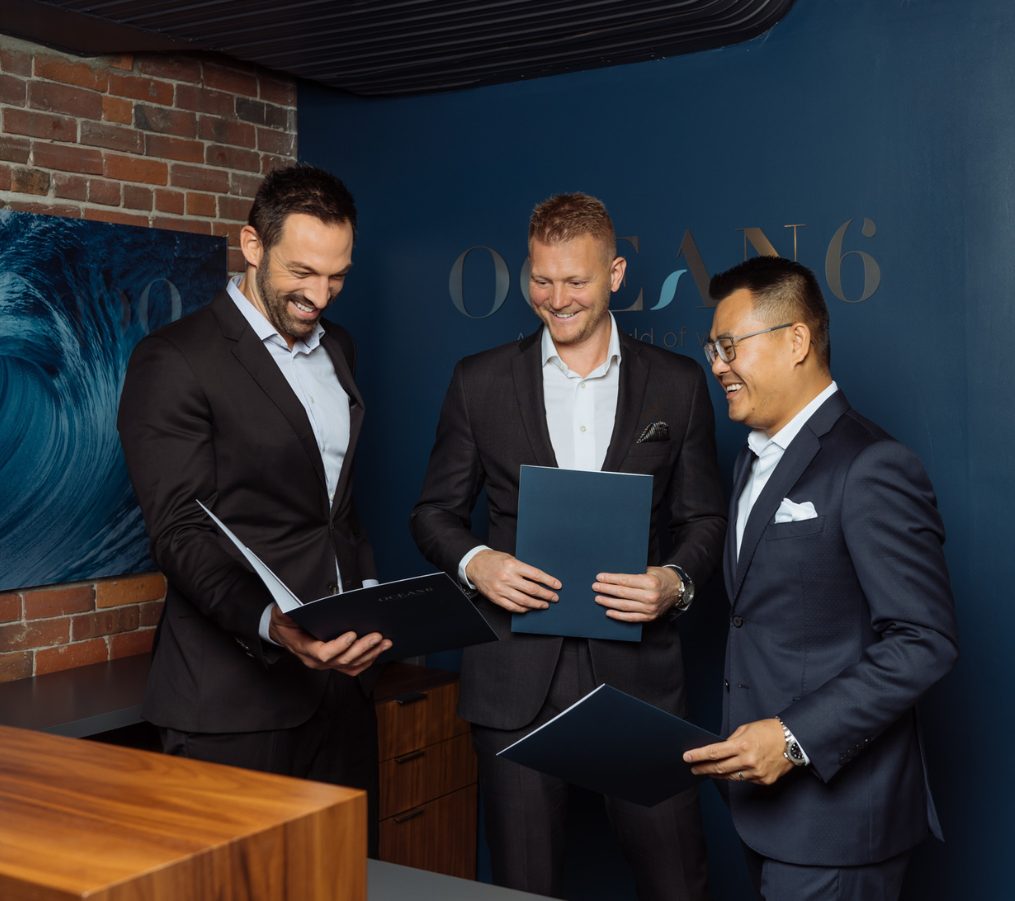 Three financial advisors standing next to each other and looking at a folder and smiling